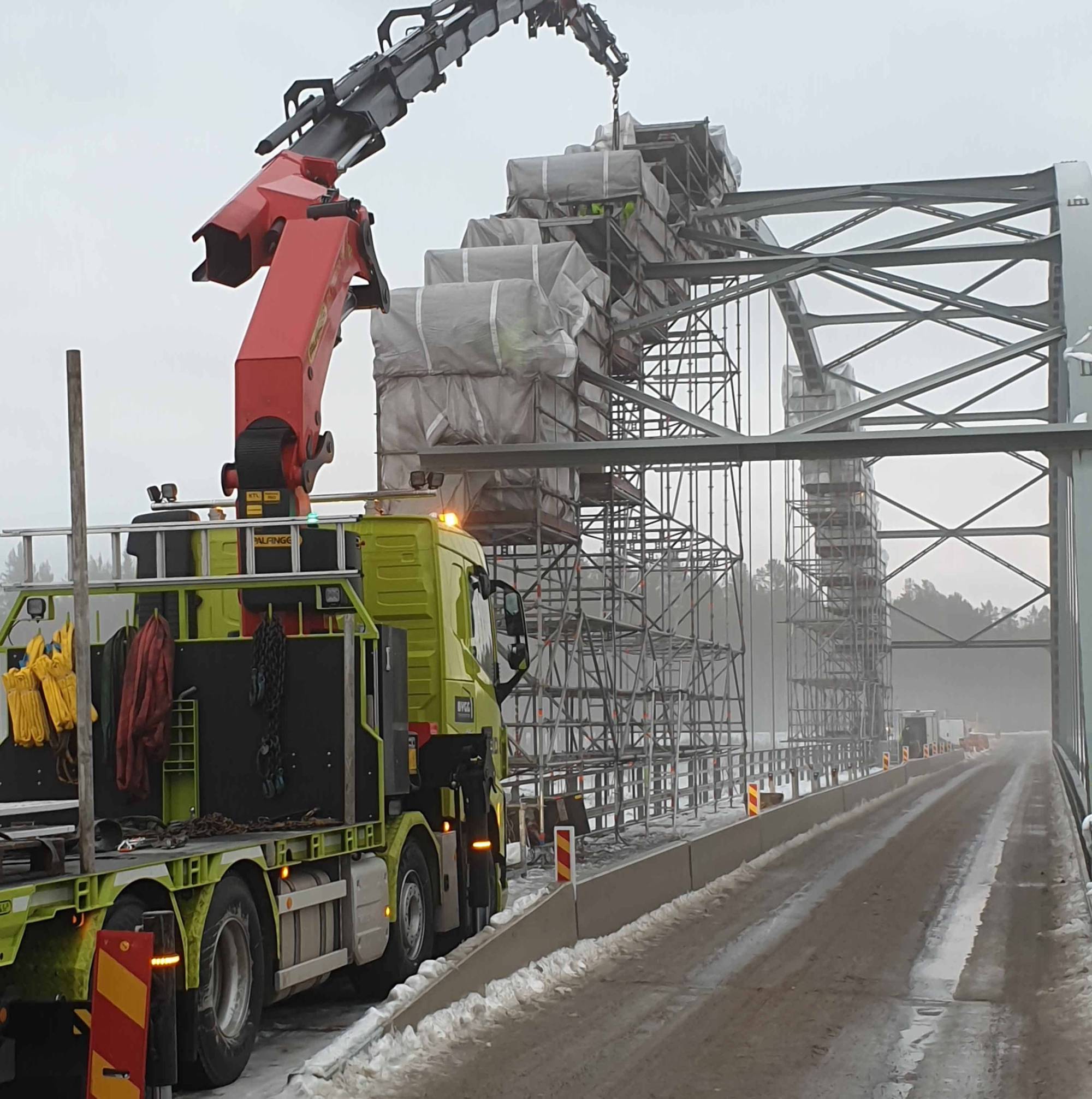 I bilden syns en bro och en lastbil som utför montage och konstruktion på bron.